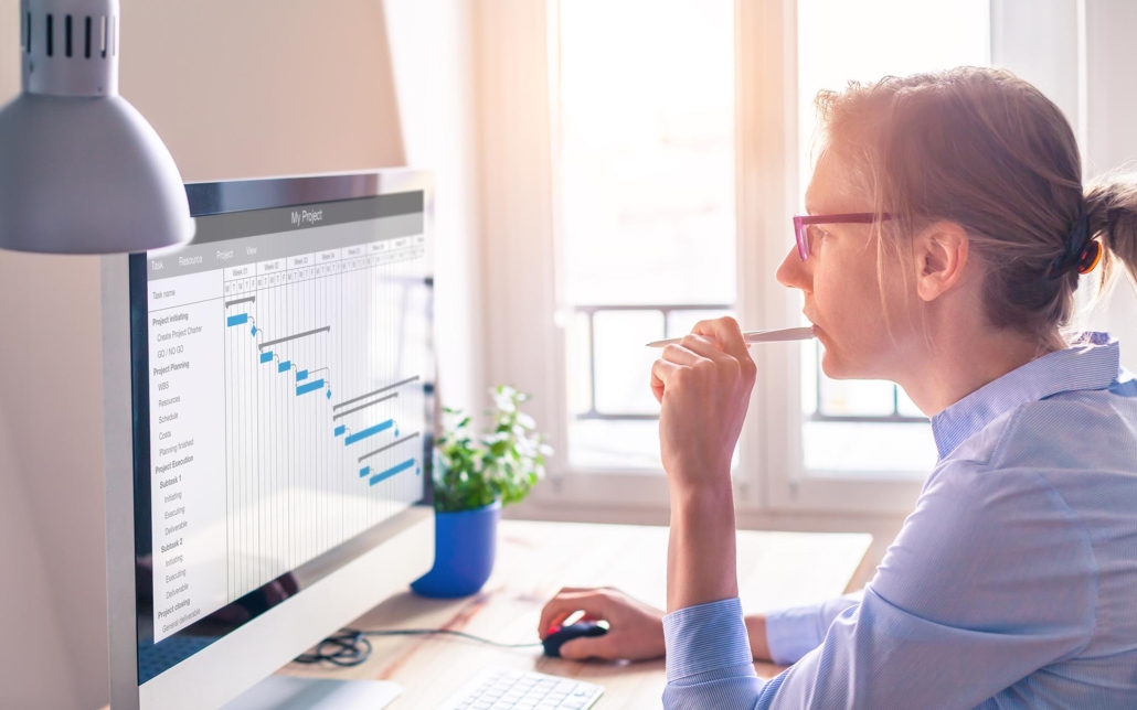 Side view of a woman looking at a Gantt Chart on her computer