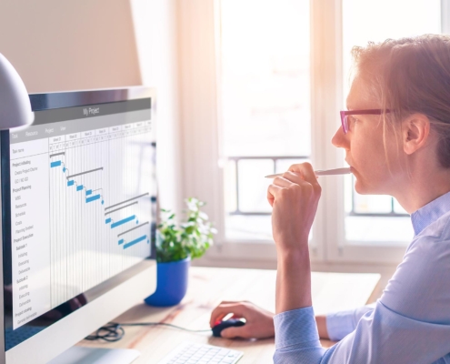 Side view of a woman looking at a Gantt Chart on her computer